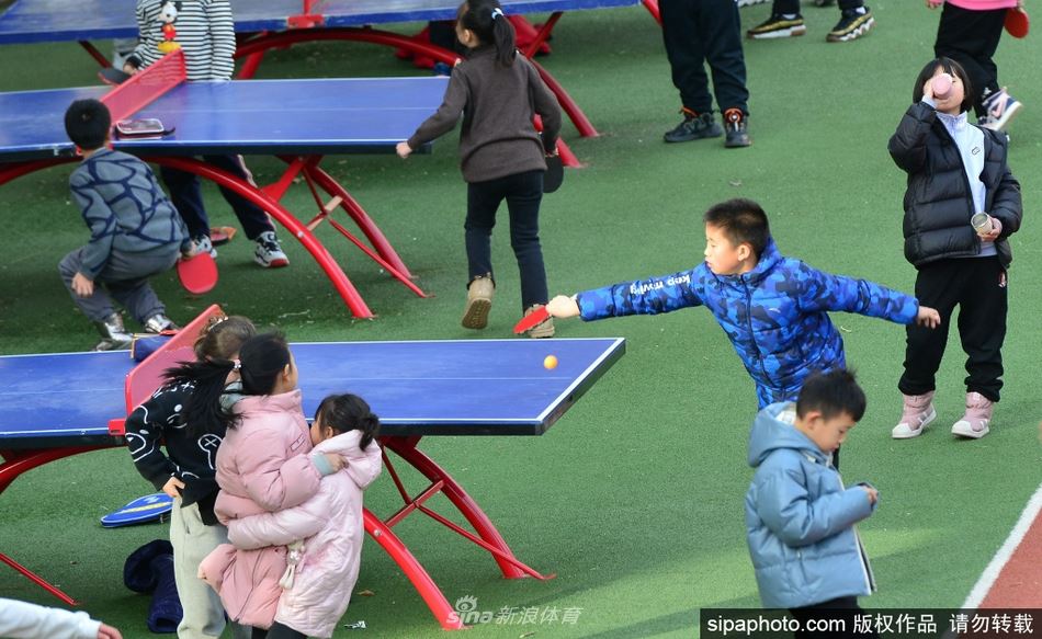 小学生们课间休息打乒乓球玩着火热都忘记了寒冷